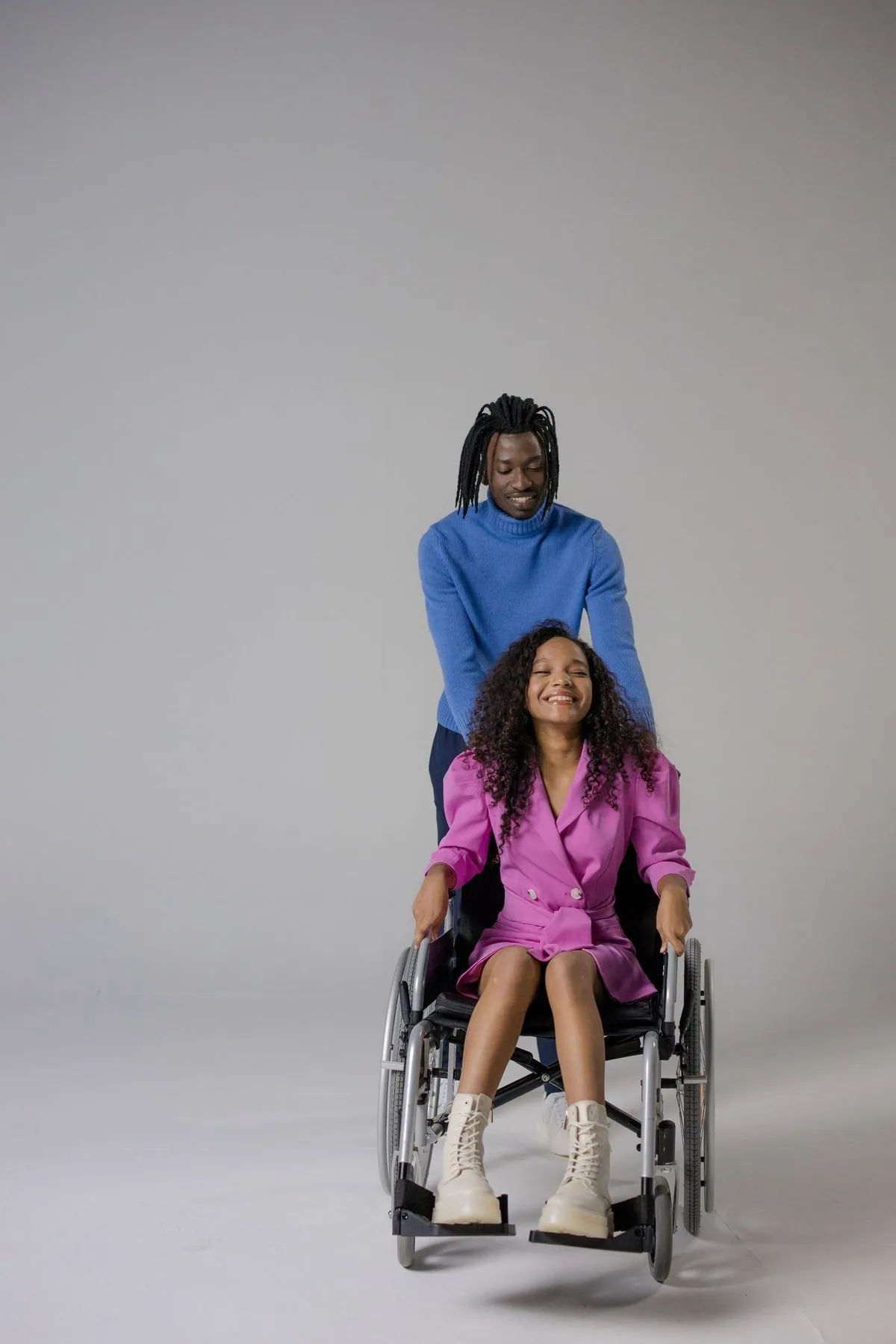 Black adult using a wheelchair with a support worker outdoors